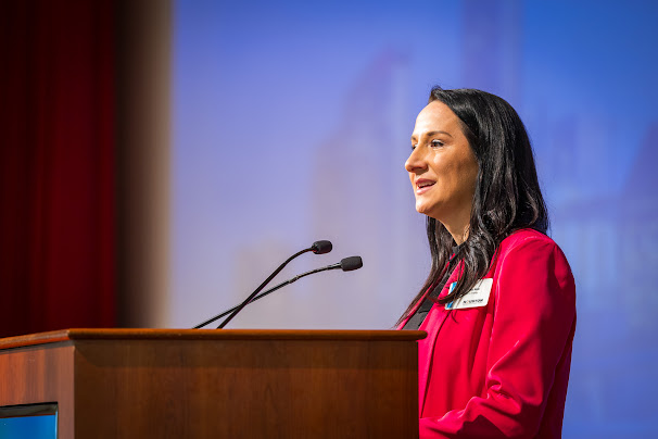 Speaker at podium in red jacket
